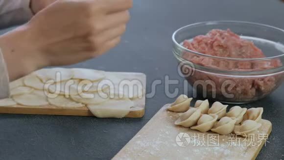 女人用肉馅包饺子，特写的手。