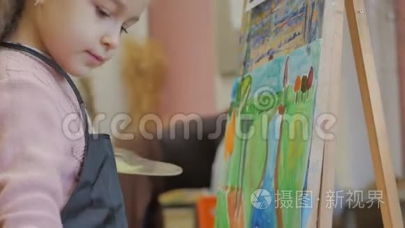 年轻的艺术家的手，小女人艺术家用画笔描绘画布，坐在桌子上画画布。 程序