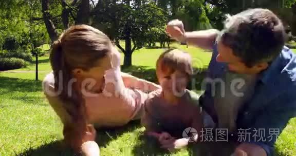 小男孩和父母对着公园里的摄像机微笑