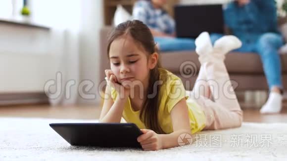 有平板电脑的女孩躺在家里的地板上