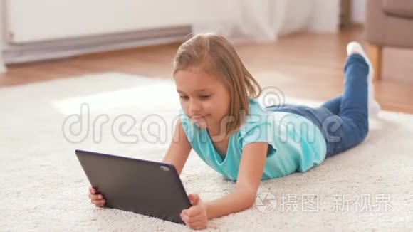 有平板电脑的女孩躺在家里的地板上