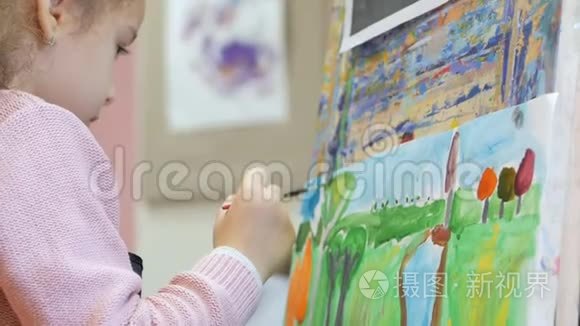 年轻的艺术家的手，小女人艺术家用画笔描绘画布，坐在桌子上画画布。 程序