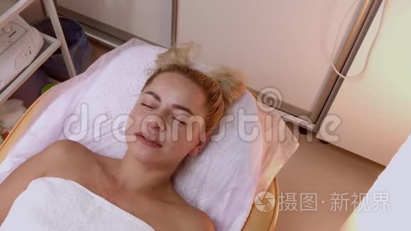 美丽的年轻女性，穿着浴袍，躺在豪华水疗沙龙等待面部护理程序