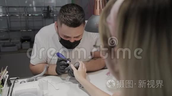 专业的美甲师男人用一种特殊的指甲油清除剂从女孩身上去除旧指甲油。