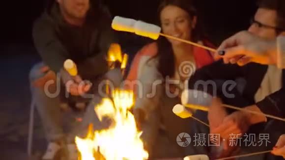 朋友们晚上在营火上烤棉花糖视频