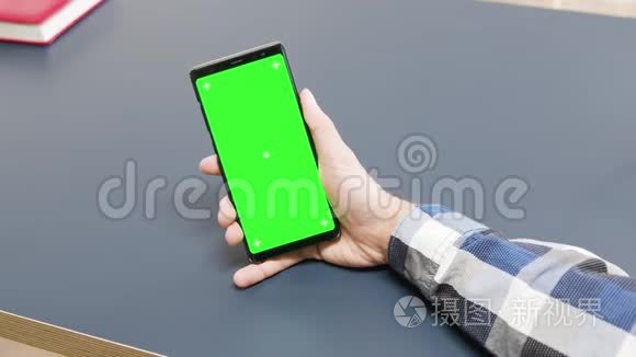 有人拿着绿色屏幕手机在桌子上视频