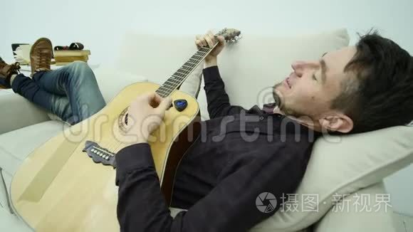 年轻人躺在沙发上弹吉他