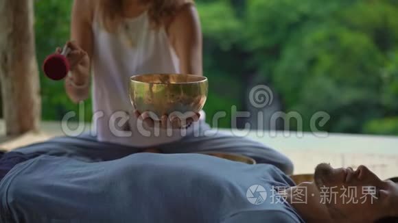 一位亚洲圣药大师为一位年轻的客户表演藏碗治疗仪式的女子拍摄的超慢镜头