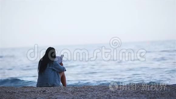 在热带白色海滩读书的年轻女子