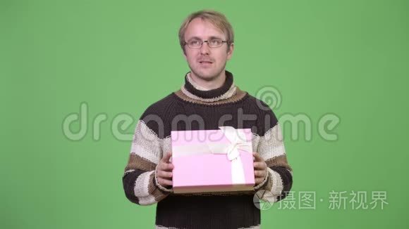 摄影棚拍摄的快乐帅哥一边思考一边拿着礼品盒