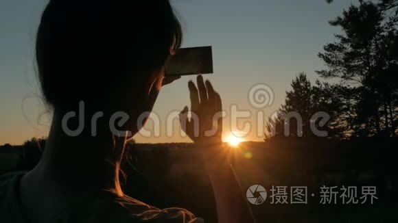 女士剪影与智能手机拍摄日落视频