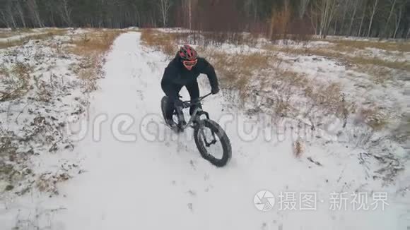 专业的极限运动运动员骑胖自行车在户外。 骑自行车在冬天的雪田，森林。 人类