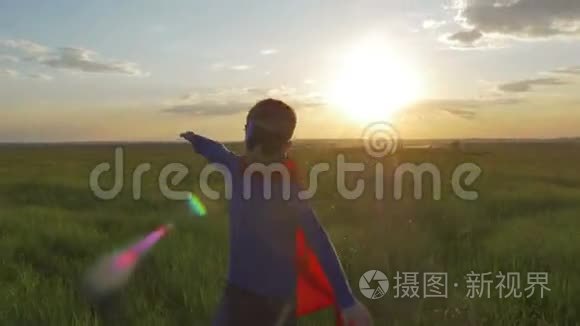 穿着超人斗篷的男孩跑在田野里，看着夕阳