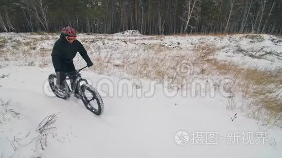 专业的极限运动运动员骑胖自行车在户外。 骑自行车在冬天的雪田，森林。 人类