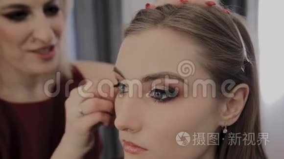 化妆师将专业化妆应用于一个美丽的年轻女孩。 化妆新概念。