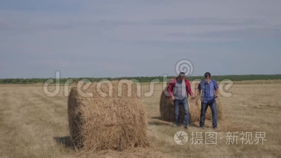 团队农业生活方式智慧农业理念.. 两个男的农民工人在田野上的草堆上散步