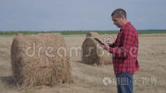 智慧农业理念.. 男子工人农民的生活方式研究干草堆在一个领域的数字平板电脑。 慢慢慢慢