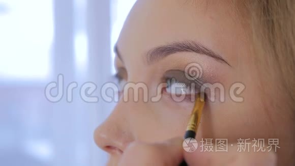 专业化妆师在模特的整个眼睛周围涂眼线