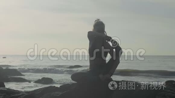 日落时剪影瑜伽练习。 勇女在沙滩上做瑜伽运动