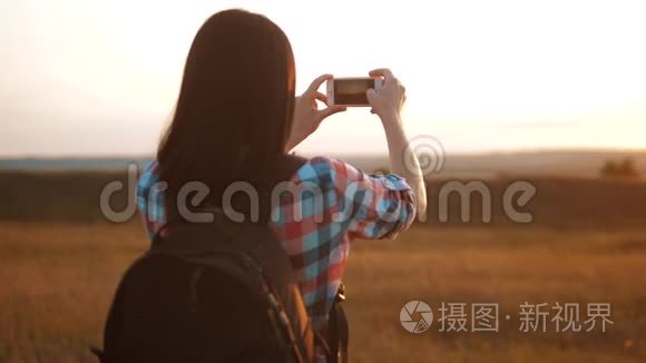 hipsterhiker剪影女孩正在手机智能手机上拍摄美丽自然日落的视频