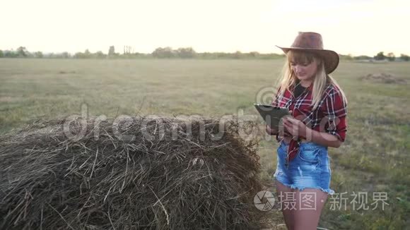 智慧农业慢动作视频概念.. 女孩农学家在干草堆里拿着平板电脑，正在学习