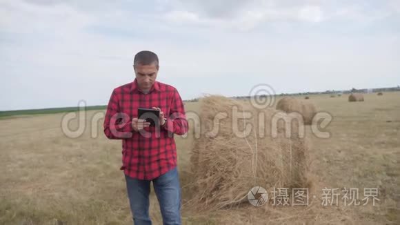 智慧农业理念.. 生活方式男子农民研究干草堆在一个领域的数字平板电脑。 慢动作