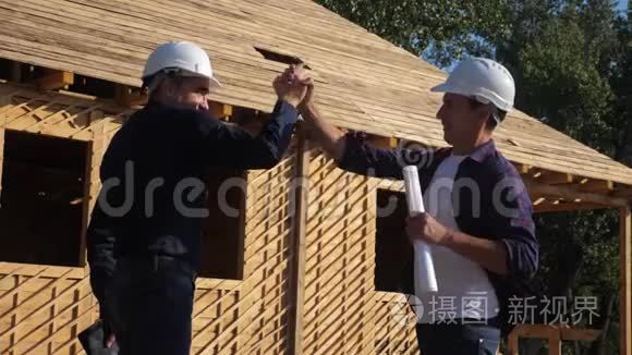 团队合作。 概念建筑构建建筑师慢动作视频.. 两个男人戴头盔的生活方式握手