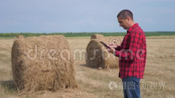 智慧农业理念.. 男子工人农民研究干草堆在一个领域的数字生活方式平板电脑。 慢慢