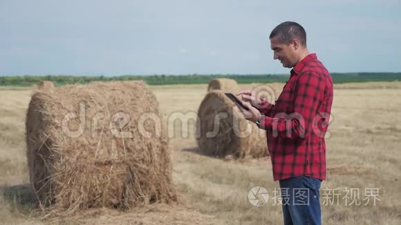 智慧农业理念.. 一名农民工人在数字平板电脑上的田野里研究干草堆。 慢速视频