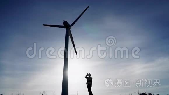 日落时带手提电脑和风车的工程师剪影