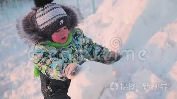 一个小孩子正在冬天的公园里玩雪。 晴朗的冬日。 新鲜空气中的乐趣和游戏。