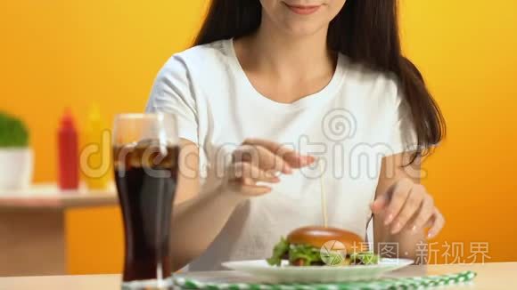 年轻女子在快餐店吃美味的汉堡包，不健康的饭菜