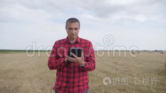 智慧农业理念.. 一个农夫在数字平板电脑上的田野里研究干草堆。 慢速视频