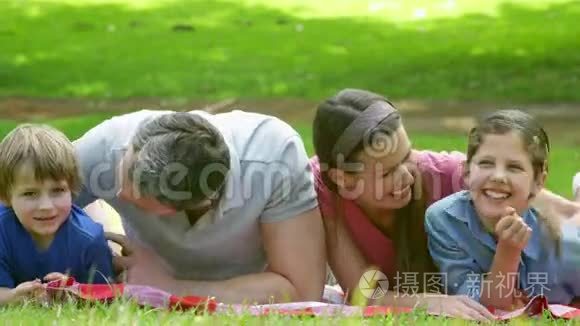 可爱的一家人躺在公园的毯子上