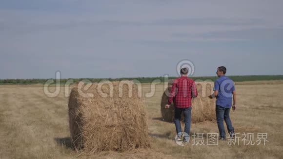 团队农业智慧农业理念生活方式.. 两个男的农民工人在田野上的草堆上散步