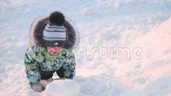一个小孩子正在冬天的公园里玩雪。 晴朗的冬日。 新鲜空气中的乐趣和游戏。