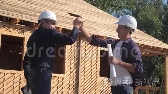 团队合作。 概念建设构建建筑师慢动作视频。 两个男人戴头盔，生活方式握手