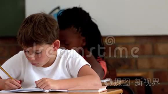 小男孩在教室里写记事本视频