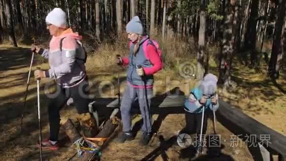 女人在大自然中行走北欧。 女孩和孩子使用跋涉棒和北欧杆，背包。 家庭旅行