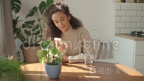 年轻的女人在厨房里用手机。