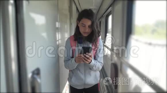 十几岁的女孩走在火车车厢里，带着生活方式背包和智能手机。 旅游运输铁路