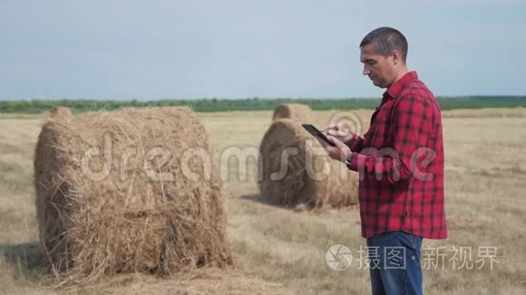 智慧农业理念.. 男子工人农民在生活方式中研究干草堆，在数字平板电脑上的田野。 慢慢慢慢