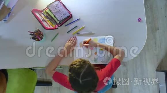 小女孩在油漆桌上画画。 女学生青少年在室内用铅笔画画
