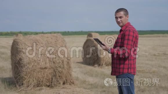 智慧农业理念.. 一名农民工人在数字平板电脑上的田野里研究干草堆。 慢速视频