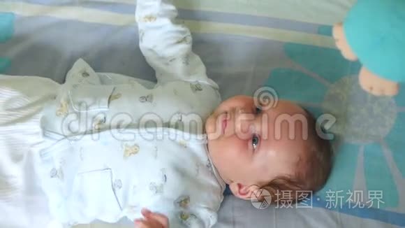小可爱的小男孩躺在婴儿床上带玩具