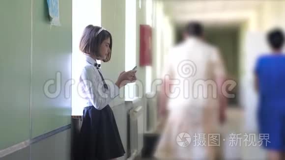 女学生教育与生活方式智能手机在学校的概念。 十几岁的少女和使用智能手机站在旁边