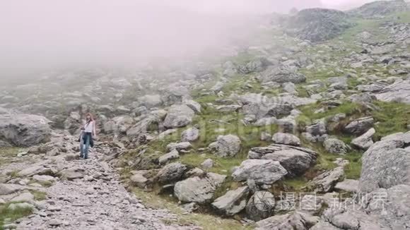 一个年轻的女徒步旅行者带着照片相机爬山。 罗马尼亚喀尔巴阡山脉