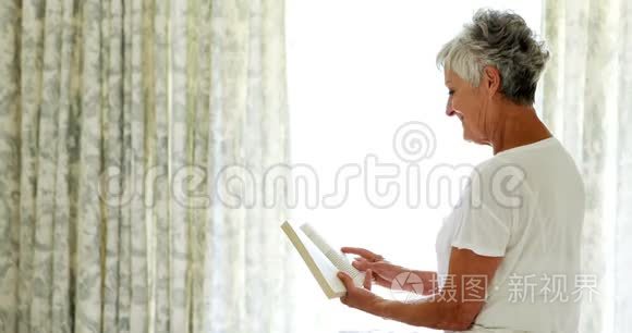 微笑的老太太在卧室看书
