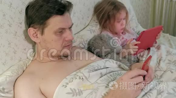 爸爸和小女儿在床上玩平板电脑视频