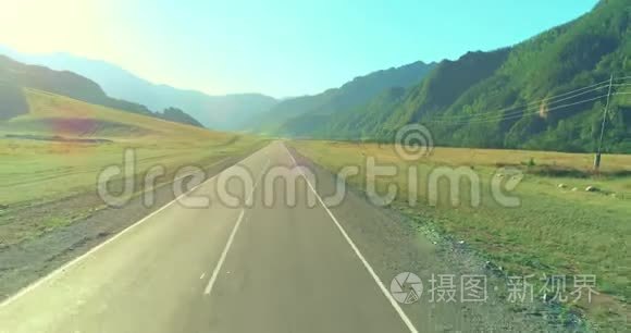 在阳光明媚的夏季早晨，低空飞越山路和草地。